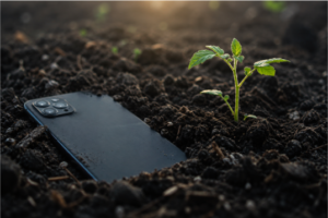 Cell phone in living soil next to a sprout
